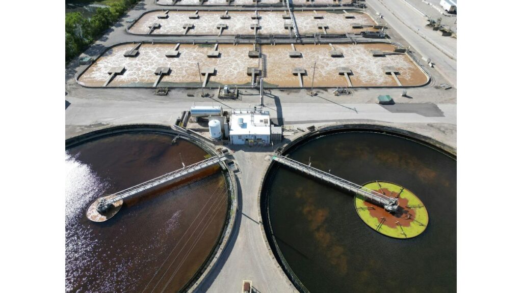 Aerial view of a water treatment facility with circular settling tanks and utility infrastructure