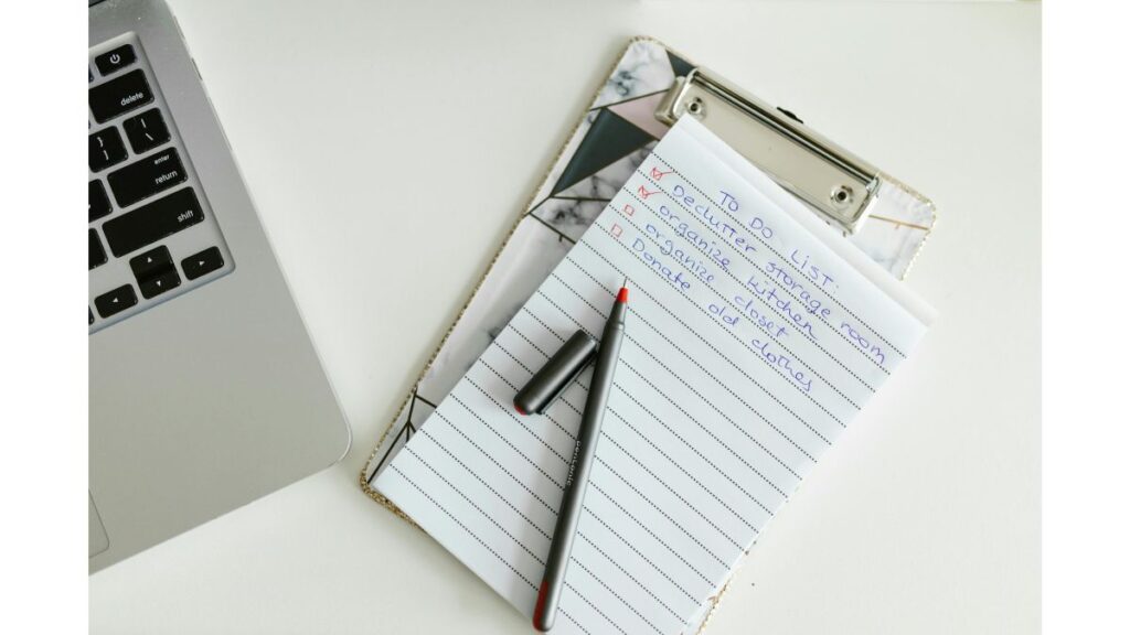 Notepad and pen on a clipboard beside a laptop, representing household water-related questions and follow-up steps