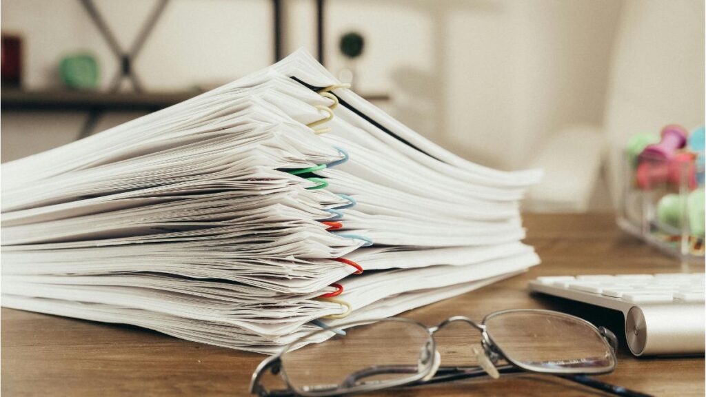 Printed documents and records spread across a desk for review